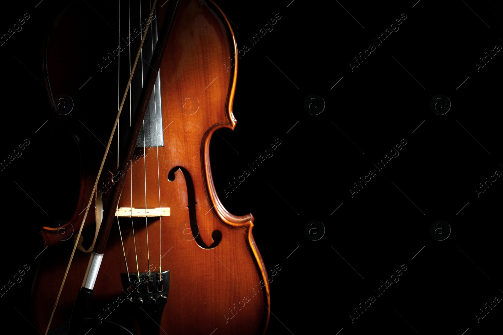 Photo of Classic violin and bow on black background. Space for text