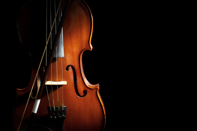 Photo of Classic violin and bow on black background. Space for text