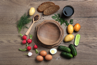 Photo of Flat lay composition of ingredients for okroshka with kvass on wooden table. Traditional Russian summer soup