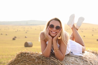 Photo of Beautiful hippie woman on hay bale in field, space for text