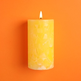 Alight scented wax candle on color background