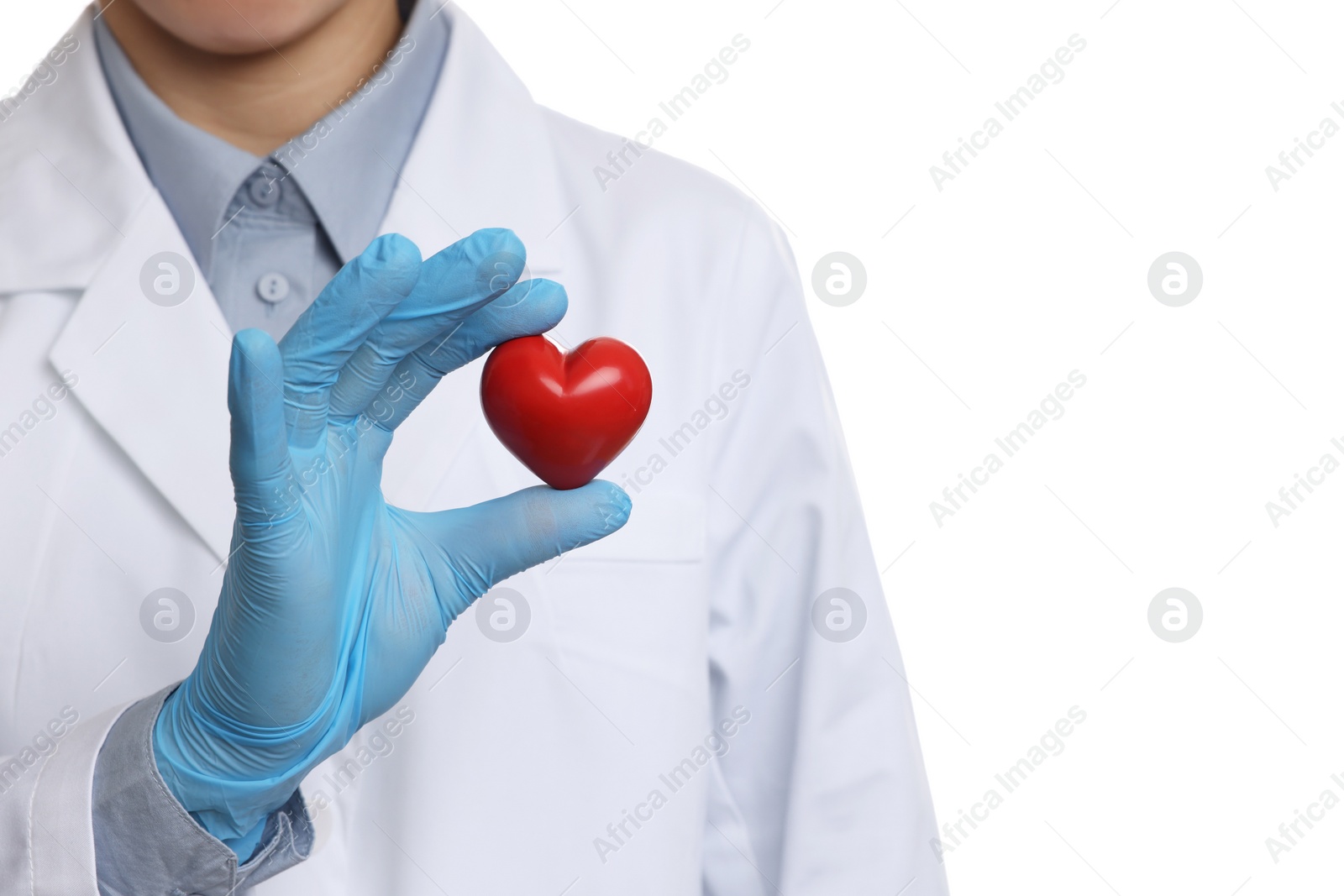 Photo of Doctor wearing light blue medical glove holding decorative heart on white background, closeup