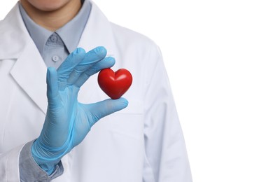 Doctor wearing light blue medical glove holding decorative heart on white background, closeup