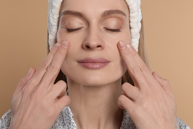 Photo of Woman massaging her face on beige background