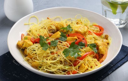 Photo of Stir-fry. Delicious cooked noodles with chicken and vegetables in bowl on table, closeup