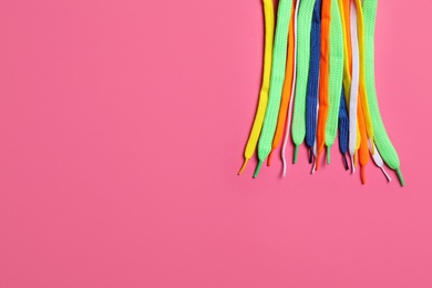 Colorful shoelaces on pink background, flat lay. Space for text