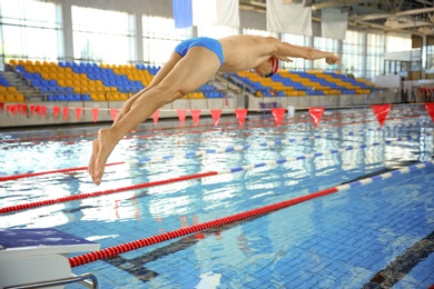 Photo of Young athletic man jumping in swimming pool