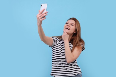 Photo of Beautiful woman taking selfie on light blue background