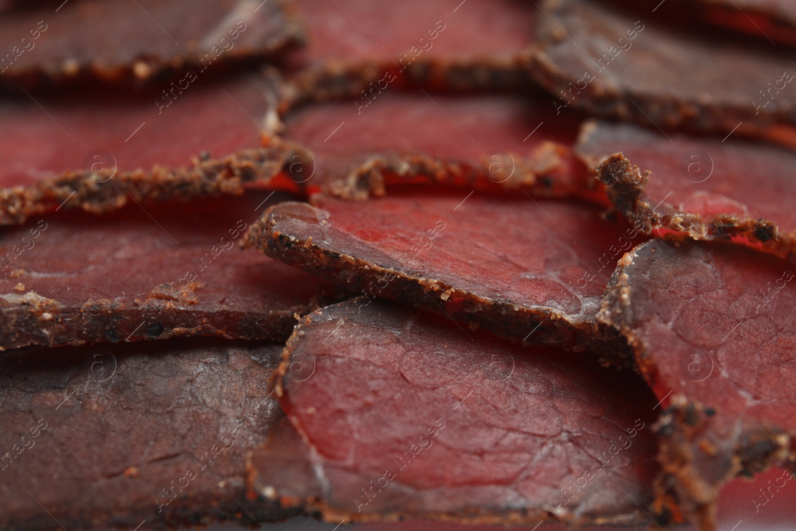 Photo of Delicious dry-cured beef basturma slices as background, closeup