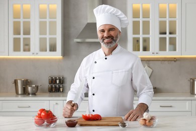 Photo of Portrait of professional chef near table with ingredients at kitchen