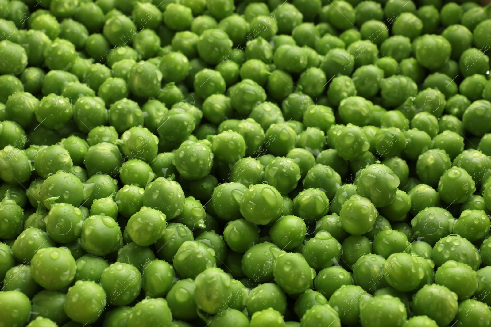 Photo of Fresh raw green peas with water drops as background, closeup