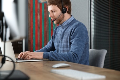 Photo of Male technical support operator with headset at workplace