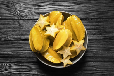 Photo of Delicious carambola fruits on black wooden table, top view