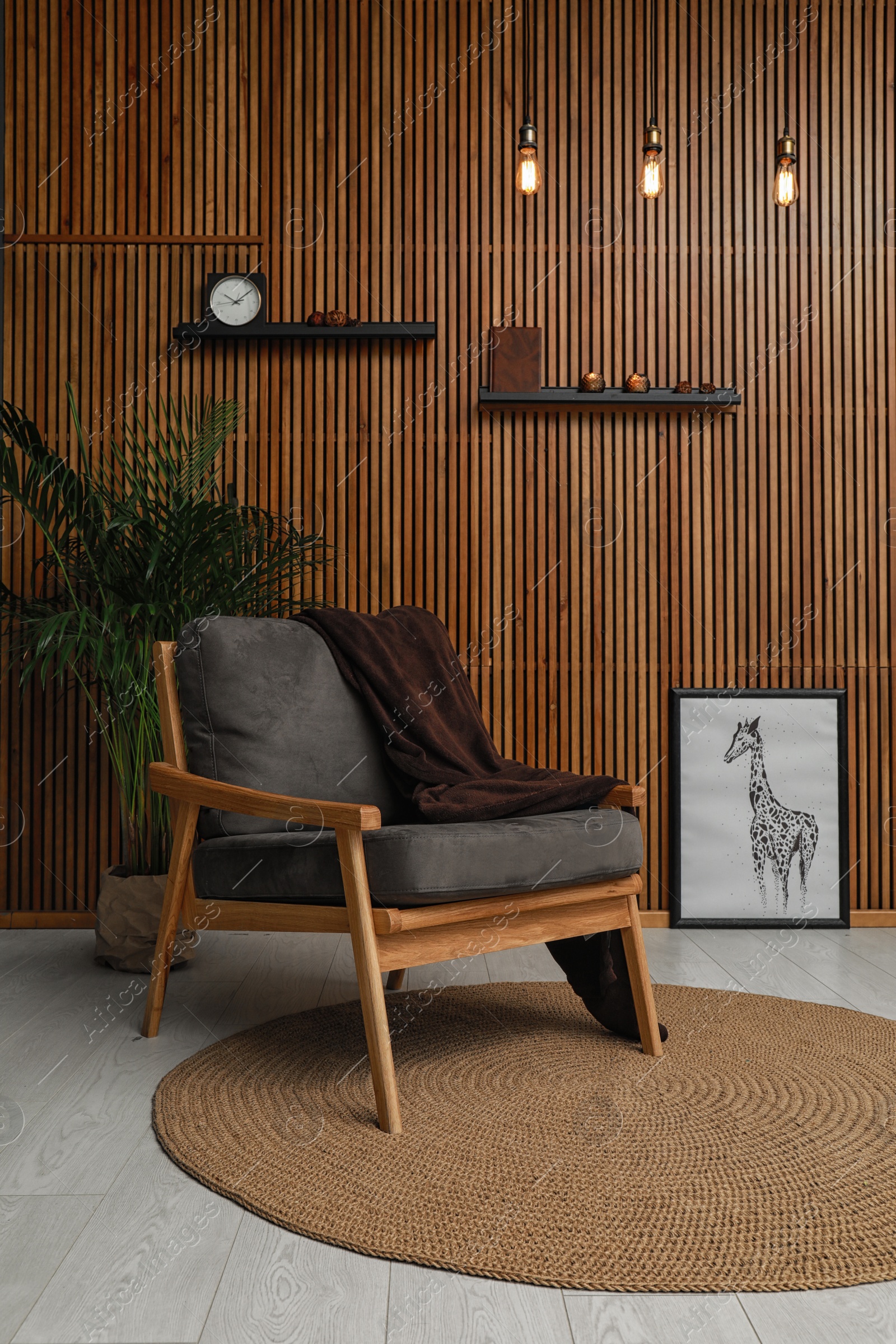 Photo of Stylish room interior with comfortable armchair and plant near wooden wall