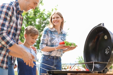 Photo of Happy family having barbecue with modern grill outdoors