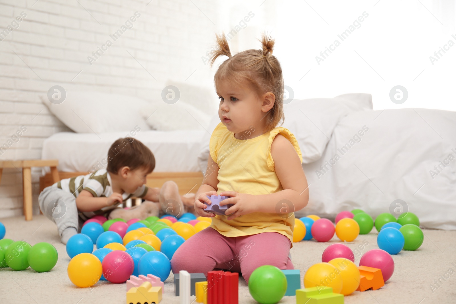 Photo of Cute little children playing with toys on floor at home