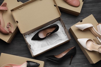 Photo of Stylish women's shoes and cardboard boxes on wooden floor, flat lay