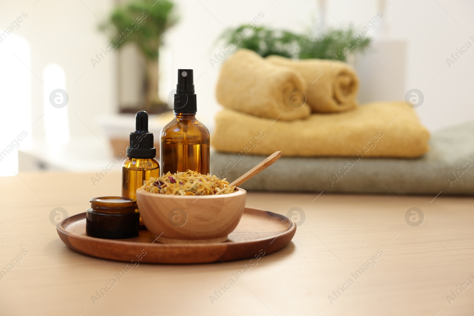 Photo of Dry flowers, bottles of essential oils and jar with cream on wooden table indoors, space for text. Spa time