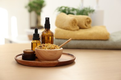 Photo of Dry flowers, bottles of essential oils and jar with cream on wooden table indoors, space for text. Spa time