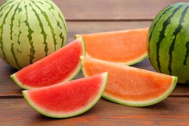 Photo of Different cut and whole ripe watermelons on wooden table