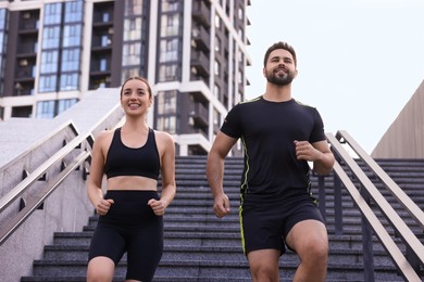 Photo of Healthy lifestyle. Happy couple running on steps outdoors, low angle view