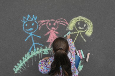 Photo of Child drawing family with chalk on asphalt, top view