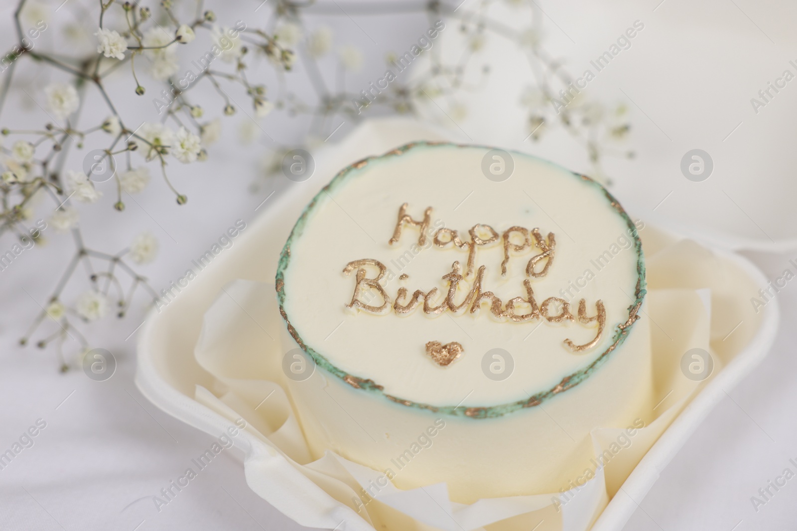 Photo of Delicious decorated Birthday cake near dry flowers on white cloth