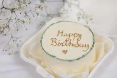 Photo of Delicious decorated Birthday cake near dry flowers on white cloth