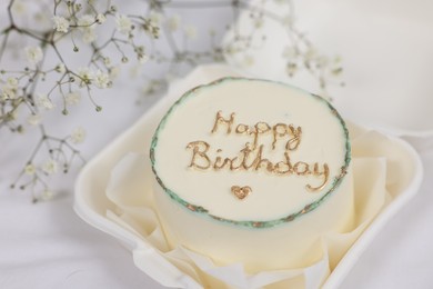 Delicious decorated Birthday cake near dry flowers on white cloth