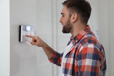 Man entering code on home security system indoors