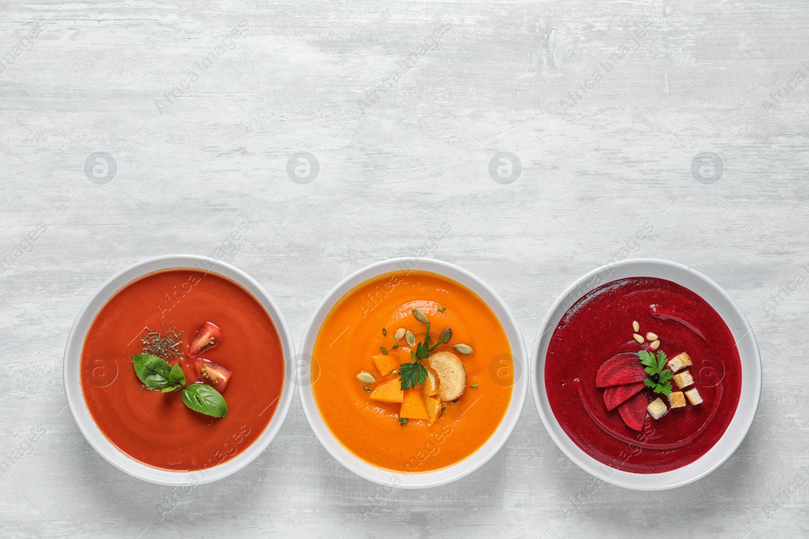 Photo of Various soups in bowls and space for text on white background, top view. Healthy food