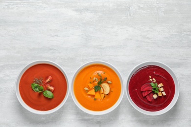 Various soups in bowls and space for text on white background, top view. Healthy food