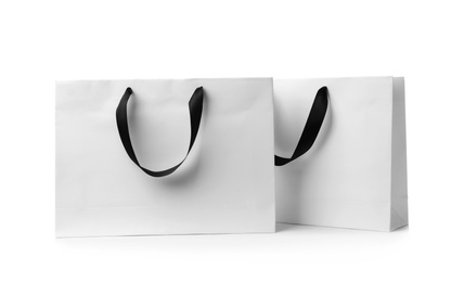 Paper shopping bags with ribbon handles on white background. Mockup for design