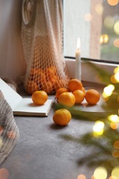 Photo of Fresh ripe tangerines and Christmas decor on grey table near window