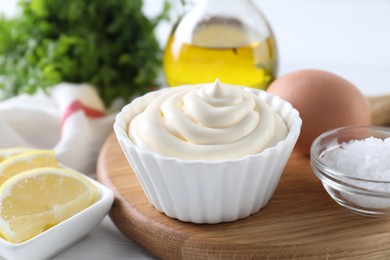 Photo of Fresh mayonnaise sauce in bowl and ingredients on table, closeup