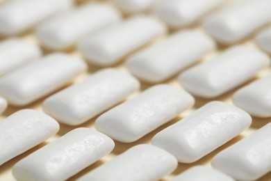 Photo of Tasty white chewing gums on beige background, closeup