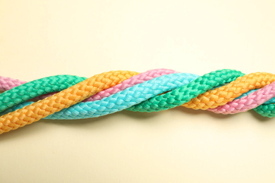 Twisted colorful ropes on beige background, top view. Unity concept