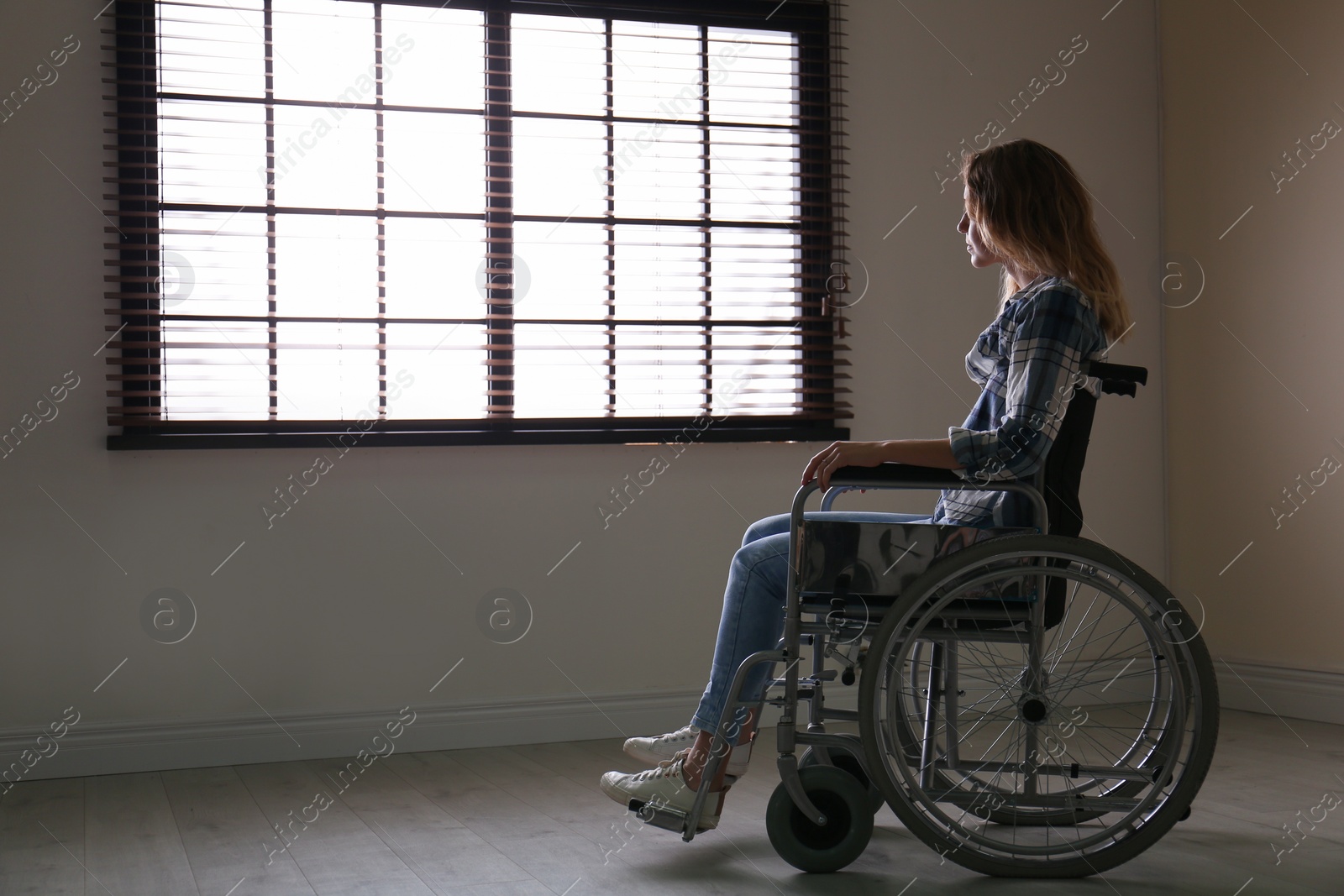 Photo of Young woman in wheelchair near window indoors