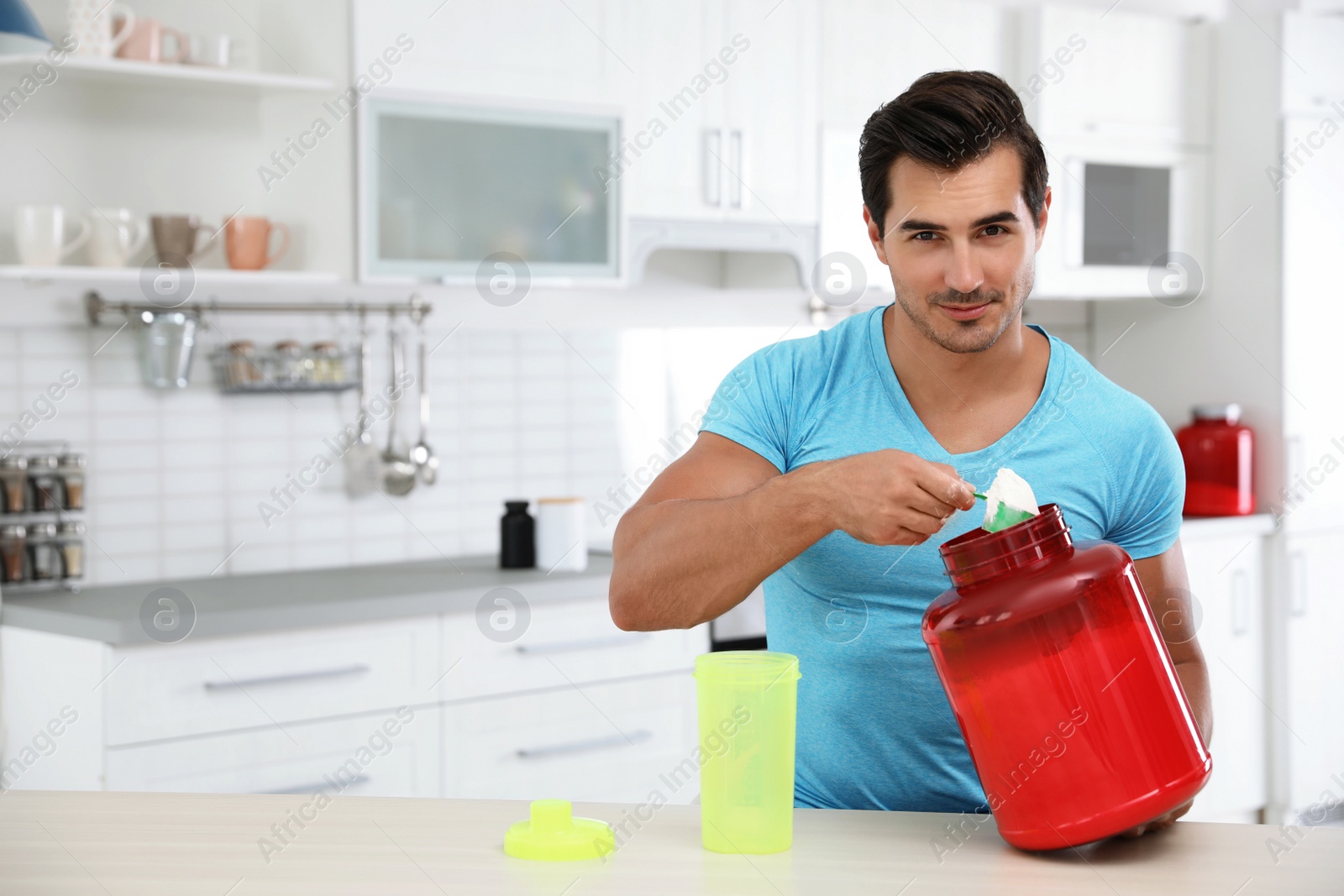 Photo of Young athletic man preparing protein shake in kitchen, space for text