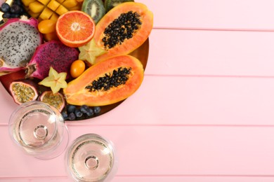Photo of Delicious exotic fruits and wine on pink wooden table, flat lay. Space for text