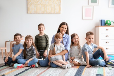 Photo of Cute little children with teacher in classroom at school