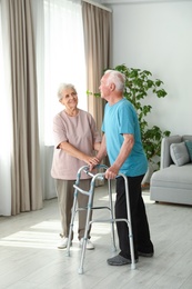 Photo of Elderly woman and her husband with walking frame indoors