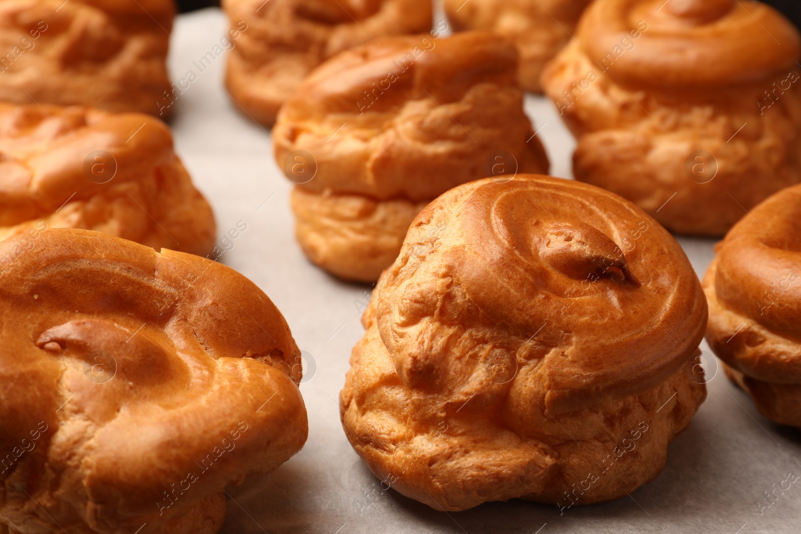 Photo of Delicious fresh profiteroles on baking pan, closeup