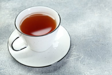 Photo of Aromatic tea in cup on grey table. Space for text