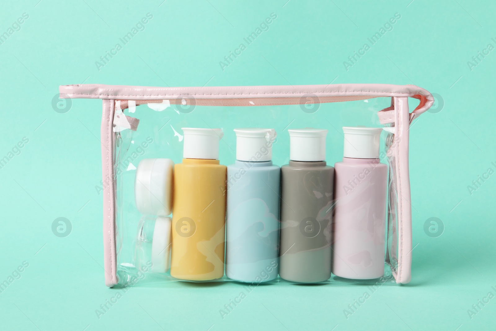 Photo of Cosmetic travel kit in plastic bag on turquoise background. Bath accessories