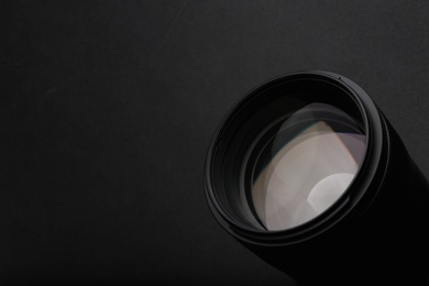 Modern camera lens on black background, closeup. Space for text