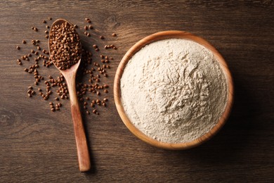 Photo of Bowl of flour and spoon with buckwheat on wooden table, flat lay