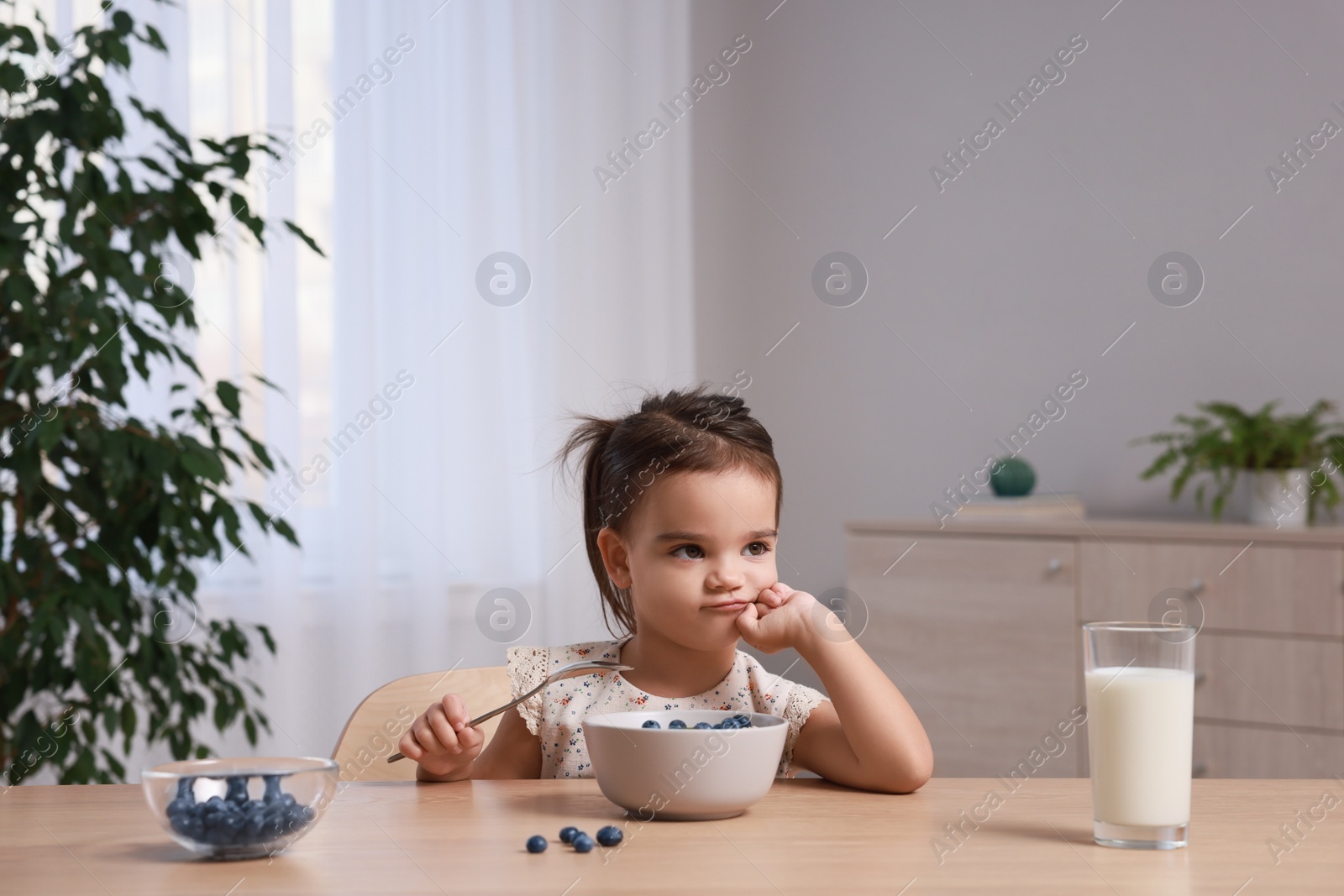 Photo of Cute little girl refusing to eat her breakfast at home