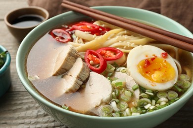 Photo of Delicious ramen in bowl on wooden table, closeup. Noodle soup