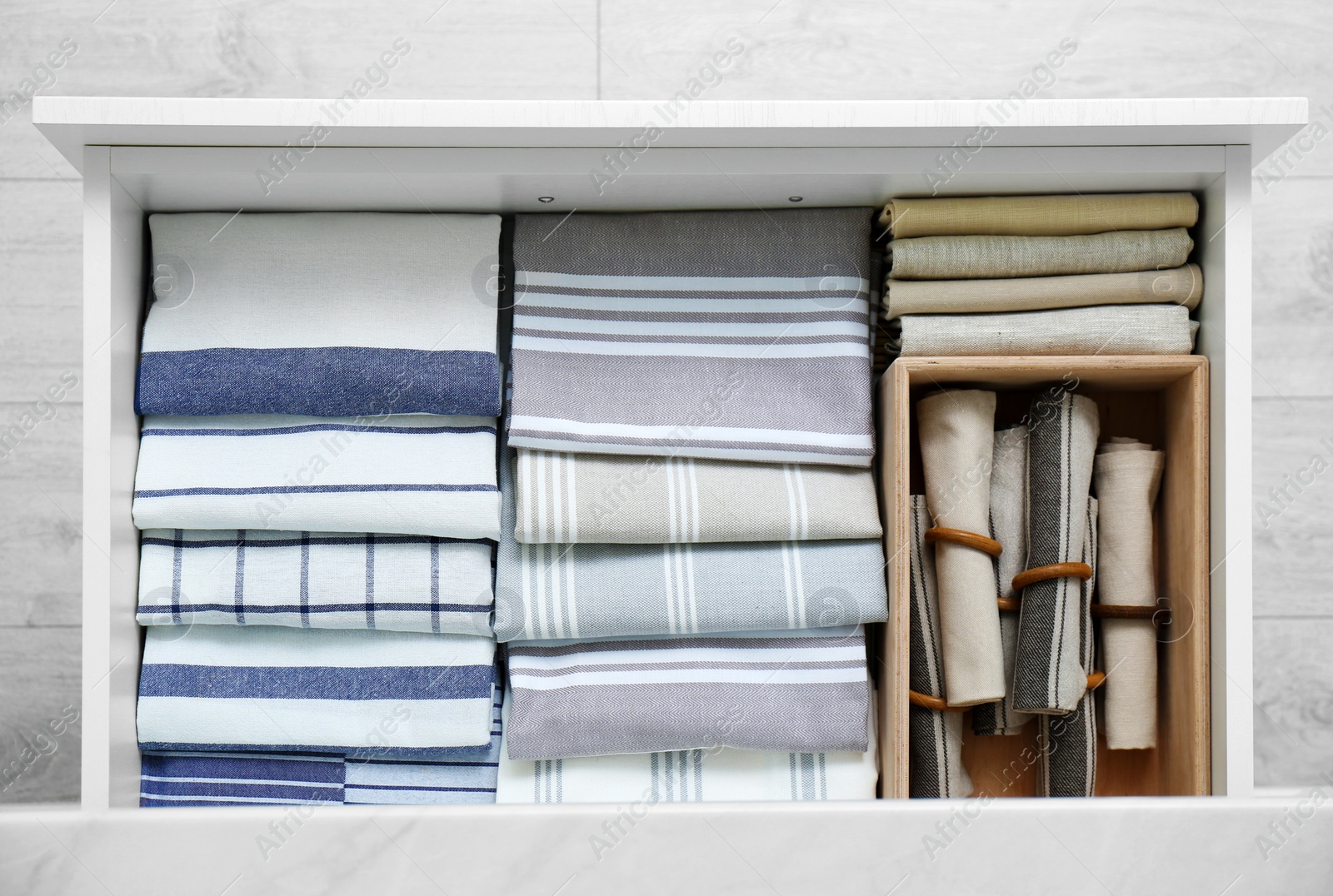 Photo of Open drawer with folded napkins and towels indoors, top view. Order in kitchen